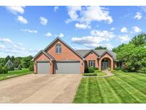 Beautiful brick home showcasing an attached three-car garage and meticulously maintained lawn at 1682 S Fox Cove Blvd, New Palestine, IN 46163
