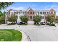 Charming townhomes with brick and siding exteriors, set back from a tree-lined street, and well-manicured landscaping at 9046 Sparta Dr, Fishers, IN 46038