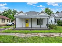 Charming single-story home with white painted brick, yellow door, covered front porch, and well-maintained yard at 1418 W 5Th St, Anderson, IN 46016