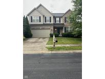 Two-story home featuring a brick and tan siding exterior, a two-car garage, and a well-manicured front yard at 14375 Leland Muse, Fishers, IN 46037