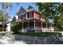 Charming red two-story home with a welcoming wrap-around porch and manicured landscaping at 189 S Jefferson St, Martinsville, IN 46151