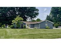 Charming single-story home with well-manicured lawn, mature trees and bright yellow front door at 540 Lazy Ln, Greenwood, IN 46142