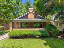 Charming brick home featuring a cozy front porch and well-manicured landscaping at 5424 Broadway St, Indianapolis, IN 46220