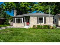 Charming stone home with a well-maintained lawn and a bright red front door at 6146 Burlington Ave, Indianapolis, IN 46220