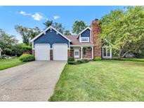 Charming blue two-story home featuring a brick chimney, two-car garage and beautifully landscaped yard at 8140 Bold Forbes Ct, Indianapolis, IN 46217