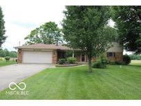 Inviting front yard view of home with a manicured lawn, mature trees, and attached two-car garage at 8905 Maze Rd, Indianapolis, IN 46259