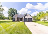 Charming home featuring an attached two-car garage, well-manicured lawn and basketball hoop on the driveway at 8925 Sunburst Cir, Indianapolis, IN 46227