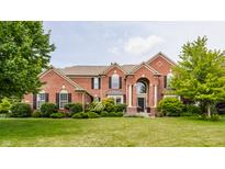 Beautiful red brick two-story home with mature trees, manicured lawn, black shutters, and an arched front entry at 9237 Rocky Cay Ct, Zionsville, IN 46077