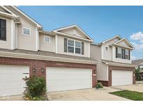 Charming townhome exterior with brick accents and a two-car garage, under a clear blue sky at 9707 Prairie Smoke Dr, Noblesville, IN 46060