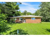 Charming single-story brick home with a metal roof and lush green lawn on a sunny day at 10159 Hodge Rd, Clayton, IN 46118