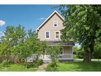 Charming two-story home with a front porch and mature trees in a well-maintained yard at 1129 Trowbridge St, Indianapolis, IN 46203