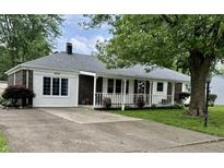Charming brick home with a covered front porch, landscaped yard and concrete driveway at 1400 Evelyn Ln, Anderson, IN 46017