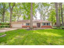 Charming single-story home with an attached garage, brick accents, and a lush green lawn at 2613 W Queensbury Rd, Muncie, IN 47304