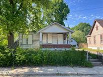 Exterior view of a boarded-up, dilapidated house with an overgrown front yard and peeling paint at 2625 E 12Th St, Indianapolis, IN 46201