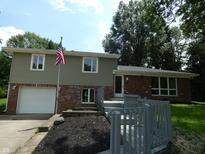 Charming two-story home with a brick and siding exterior, lovely landscaping, and an American flag at 3518 Woodale Rd, Indianapolis, IN 46234