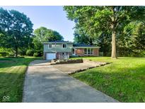 Charming two-story home with a brick and siding exterior, a spacious driveway, and mature trees at 3518 Woodale Rd, Indianapolis, IN 46234