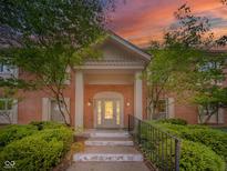 Stunning brick home featuring a covered entrance with white pillars and beautifully landscaped front yard at 7317 Lions Head Dr # A, Indianapolis, IN 46260