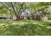 Charming one-story brick home featuring a well-manicured lawn and mature trees providing ample shade at 8246 Windcombe Blvd, Indianapolis, IN 46240