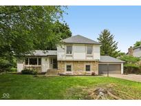 Charming home with a stone facade and well-maintained lawn with mature trees and an attached two car garage at 10778 Haverstick Rd, Carmel, IN 46033