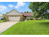 Charming brick home featuring a well-manicured lawn and attached two-car garage on a beautiful sunny day at 1106 Summer Way Ct, Shelbyville, IN 46176