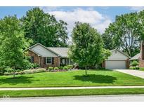 Brick home with attached garage, well-kept lawn, and colorful flower landscaping at 1237 Driftwood Dr, Carmel, IN 46033