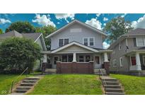 Charming two-story home featuring a covered front porch with brick accents and a well-maintained lawn at 1427 N Lasalle St # 1427, Indianapolis, IN 46201