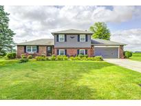 Charming two-story brick home with well-manicured lawn, flower beds, and an attached two car garage at 303 E County Road 500 N, Pittsboro, IN 46167
