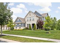 Beautiful two-story home with a stone and siding exterior, manicured lawn, and mature trees at 3720 Abney Highland Dr, Zionsville, IN 46077