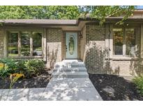 Brick home entrance with an oval window door, concrete steps, and dark mulch landscaping at 604 Oak Blvd W Dr, Greenfield, IN 46140
