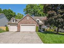 Charming two-story brick home with a well-manicured lawn and a spacious three-car garage and driveway at 6465 Robinsrock Dr, Indianapolis, IN 46268