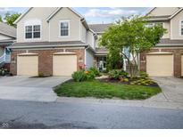 Charming townhome with a brick facade, attached garage, and well-manicured lawn with colorful landscaping at 9525 Longwell Dr, Indianapolis, IN 46240