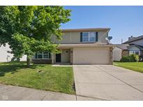 Two-story home featuring a tan facade, green shutters, a two-car garage and mature landscaping at 10222 Arapahoe Dr, Indianapolis, IN 46235