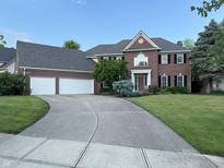 Traditional brick home features a well-manicured lawn, three-car garage and a long curved driveway at 13221 Griffin Run, Carmel, IN 46033