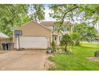 Charming two-story home with tan siding, attached garage and well-manicured lawn and garden in front at 1357 Brownswood Dr, Brownsburg, IN 46112