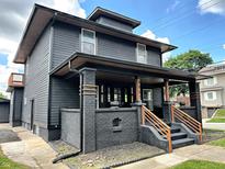 Beautifully renovated two-story home with a covered front porch, black siding and meticulously landscaped yard at 3962 Graceland Ave, Indianapolis, IN 46208