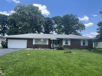 Charming brick home with a well-manicured lawn, attached garage and mature trees in a desirable neighborhood at 7725 S Oak Dr, Indianapolis, IN 46227