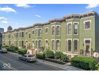 Row of green painted townhomes with bay windows, black iron fences, and manicured landscaping at 914 N Alabama St, Indianapolis, IN 46202
