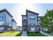Modern townhomes feature brick and metal siding, landscaped lawns and entryways with concrete steps at 13301 Minden Dr, Fishers, IN 46037