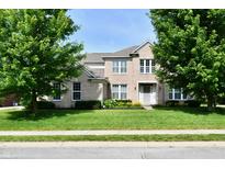 Inviting two-story home with lush green lawn, mature trees, and blooming flowerbeds enhancing its curb appeal at 14082 Brazos Dr, Carmel, IN 46033