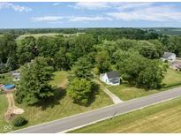 Aerial view of a quaint white home surrounded by mature trees and a vast, lush green lawn at 16000 W 700 S, Anderson, IN 46017