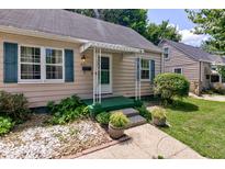 Charming home's front porch with green trim, white awning, and landscaped garden beds at 315 W 43Rd St, Indianapolis, IN 46208