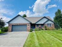 Charming single-story home with a brick exterior, a well-manicured lawn and a two car garage at 3418 S Rosewind Dr, New Palestine, IN 46163