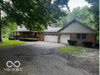 Inviting brick home featuring a large porch, mature trees, and an ample driveway at 3815 Briar Rdg, Monrovia, IN 46157