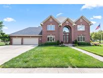 Stunning two-story brick home featuring a three-car garage and well-manicured front lawn at 4465 W Woodbridge Ln, New Palestine, IN 46163