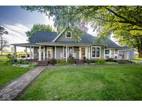 Charming home featuring a wraparound porch, lush lawn, and meticulous landscaping creating curb appeal at 6012 N 200 W, Greenfield, IN 46140