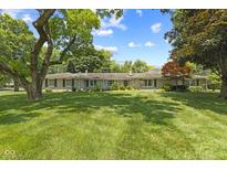 Ranch home with stone accents, mature trees, manicured lawn, and blue skies at 618 Mellowood Dr, Indianapolis, IN 46217