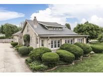 Beautiful stone home with a well-maintained front yard featuring manicured bushes and lush greenery at 6649 Madison Ave, Indianapolis, IN 46227