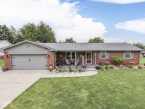 Charming brick home featuring an attached garage, lush green lawn, and vibrant flower beds at 784 S Restin Rd, Greenwood, IN 46142