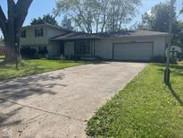 Charming exterior featuring a white brick facade, attached garage, and well-maintained front lawn at 8008 Cherington Dr, Indianapolis, IN 46227