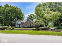 Charming brick and green two-story home with mature trees and manicured landscaping at 8315 Union Chapel Rd, Indianapolis, IN 46240